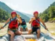Sun Kosi River Rafting: A Grade II-V Technical Analysis A fit young couple in helmets and life jackets energetically paddling a raft through a large rapid on the Sun Kosi river in Nepal.
