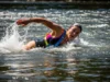 Whitewater Self-Rescue: The Aggressive Swimming Framework A full-body shot of a fit woman in a swimsuit and life jacket aggressively swimming through whitewater rapids.