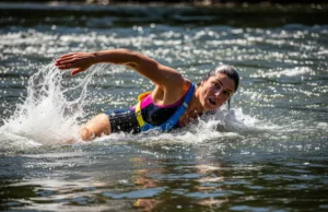 Whitewater Self-Rescue: The Aggressive Swimming Framework A full-body shot of a fit woman in a swimsuit and life jacket aggressively swimming through whitewater rapids.