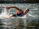 Whitewater Self-Rescue: The Aggressive Swimming Framework A full-body shot of a fit woman in a swimsuit and life jacket aggressively swimming through whitewater rapids.