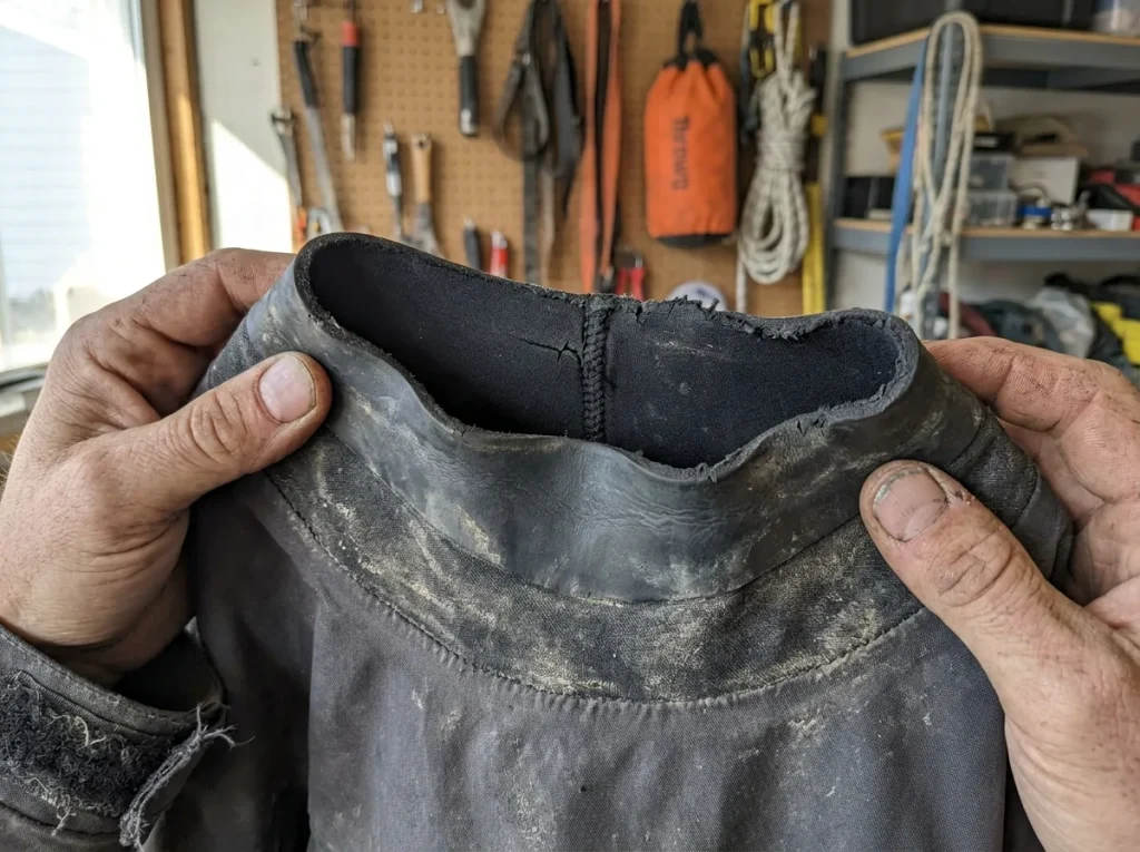 Close-up of a stretched, worn neoprene neck gasket on an aging splash jacket