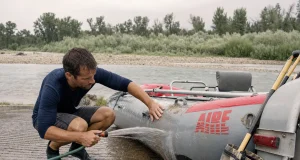 Why Rafting Gear Maintenance Isn’t a Once-a-Year Job Boater rinsing sand off an inflatable raft at a river takeout, rafting gear maintenance