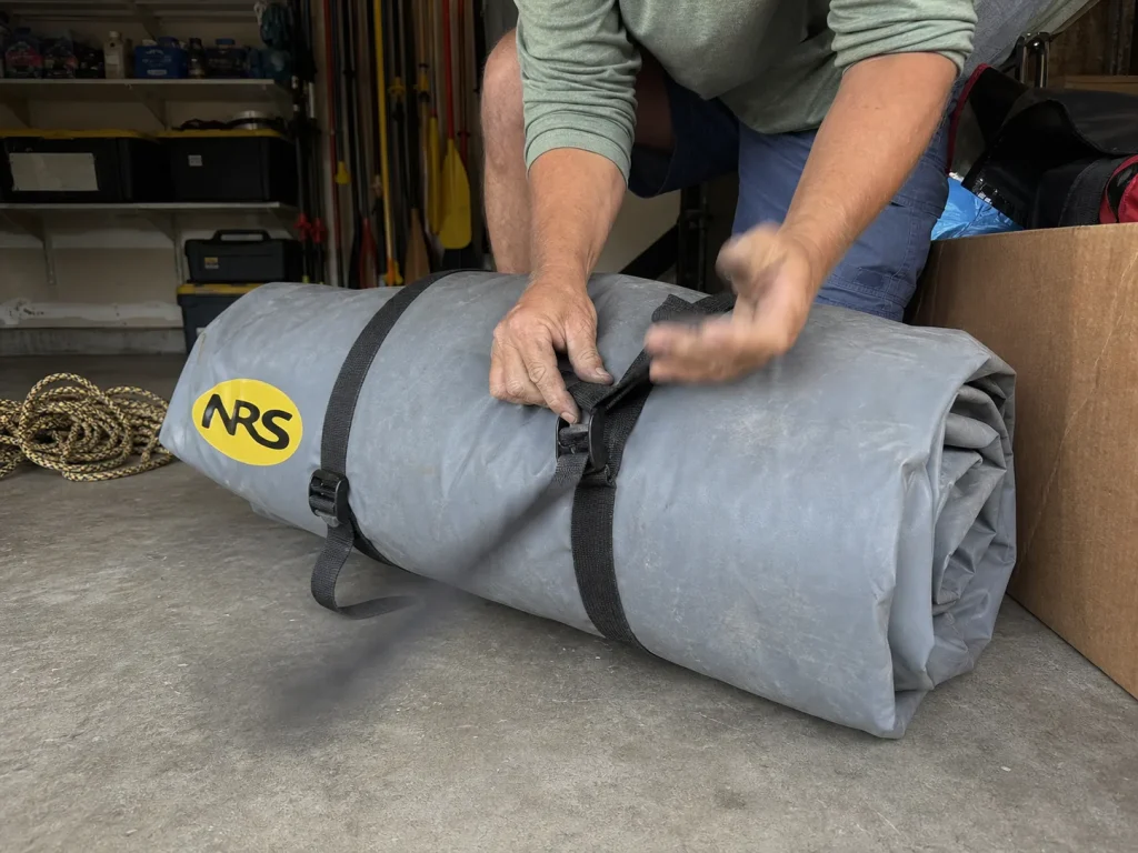 Deflated raft rolled and strapped for off-season storage in a garage