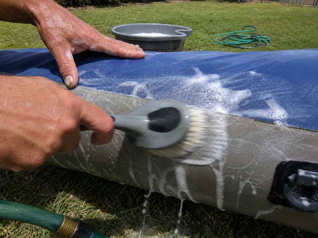 Scrubbing a raft tube with a soft brush and mild soap during cleaning
