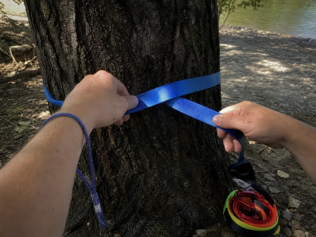 Sewn prusik loop and tubular webbing from a raft pin kit held in hand at a riverside anchor