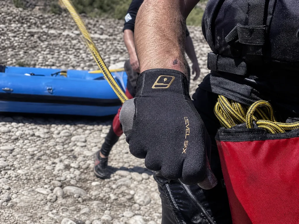 Gloved hand gripping a throw bag rope, showing dexterity for a cold-water rescue