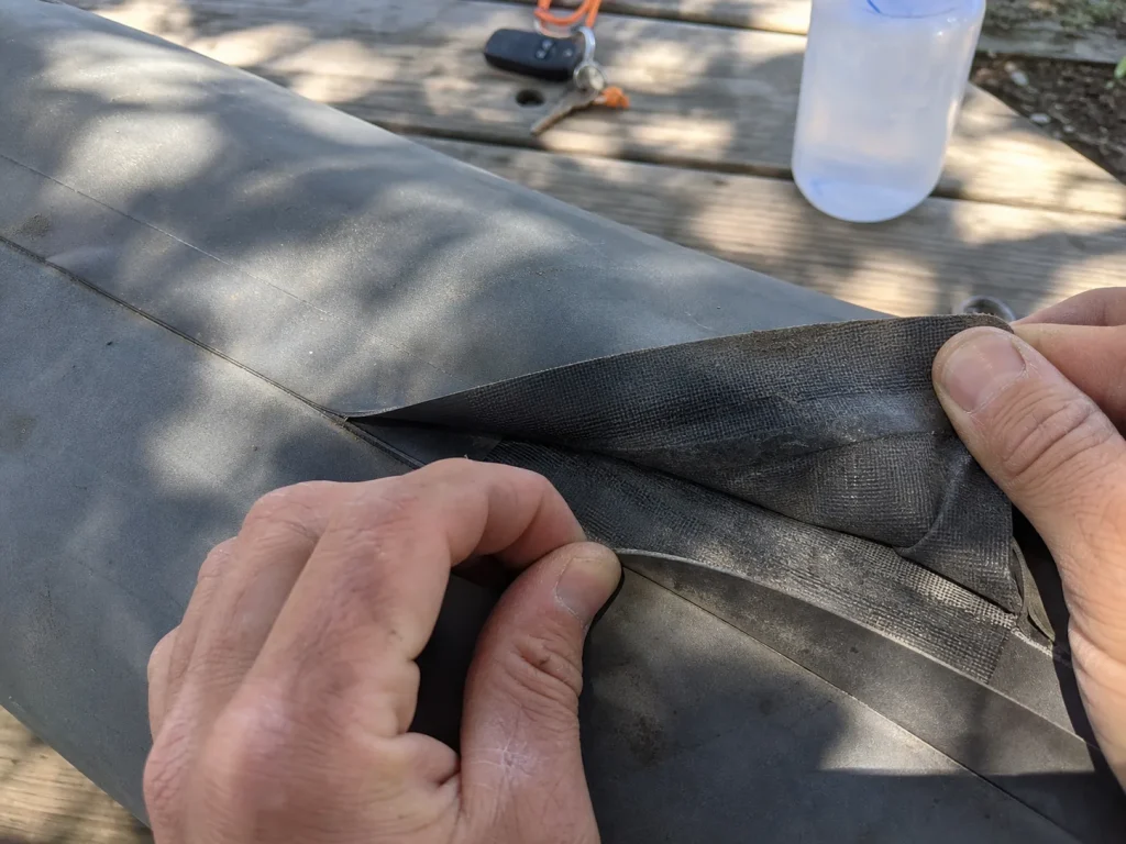 Hands folding back a raft tube to compare inside and outside color for material ID