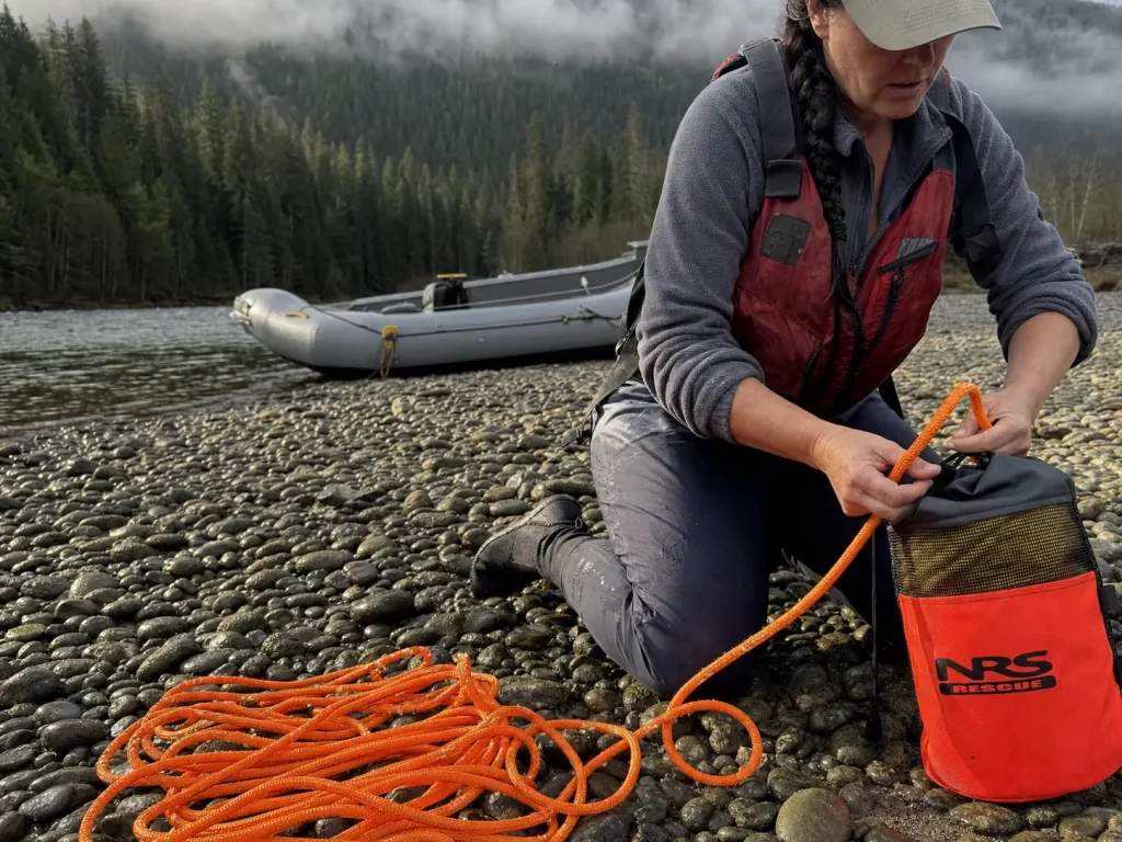 Orange rescue throw rope stacked on a gravel bar being checked as a raft pin kit haul line