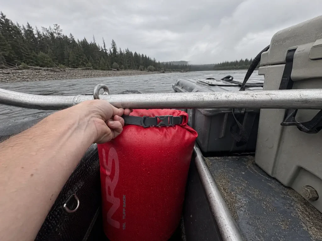 Red dry bag holding a raft pin kit strapped within reach on a rigged raft frame