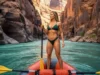 A River Guide’s Career: The Complete Blueprint A female river guide with an athletic build stands on her raft in a vast, beautiful river canyon, looking downstream.