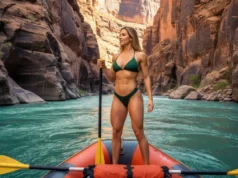 A River Guide’s Career: The Complete Blueprint A female river guide with an athletic build stands on her raft in a vast, beautiful river canyon, looking downstream.