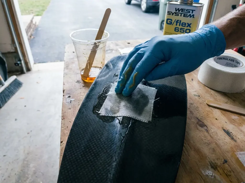 Wetting out fiberglass cloth into flexible epoxy over a cracked paddle blade