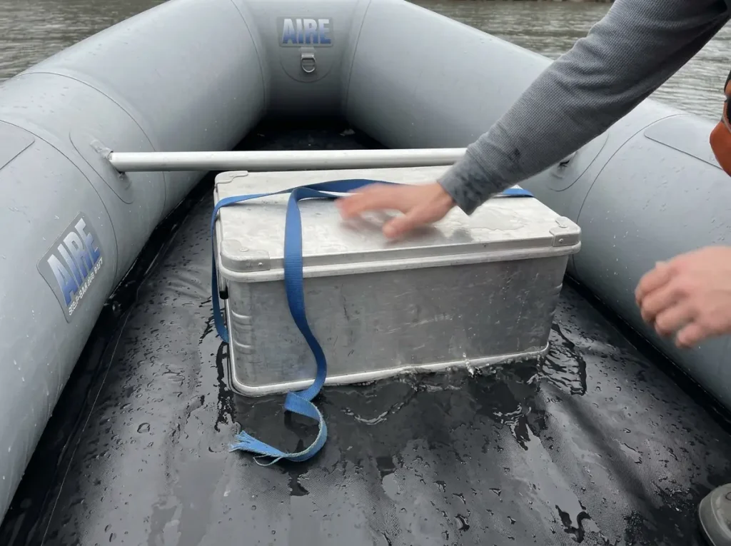 Dry box strapped flat to a flexing raft floor showing the wrong rigging that fails in whitewater