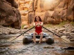 Mastering Low Water Rowing: Techniques for Bony Runs A beautiful, athletic woman skillfully rowing a cataraft through a challenging, shallow, and rocky river section under bright sunlight.
