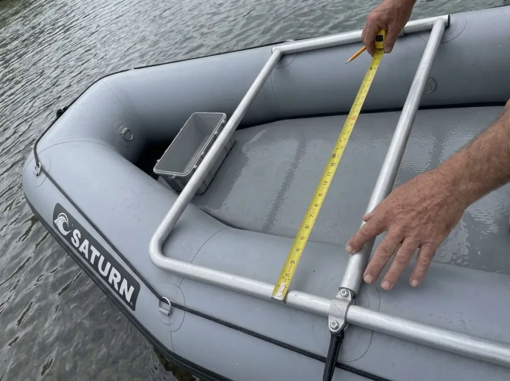 Measuring a raft frame bay with a tape before sizing a dry box to fit between the crossbars