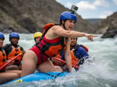 Rafter-Led Rescue: What To Do if Your Guide Falls Out A beautiful and capable woman in a whitewater raft takes charge, pointing and giving commands during an emergency rescue situation.
