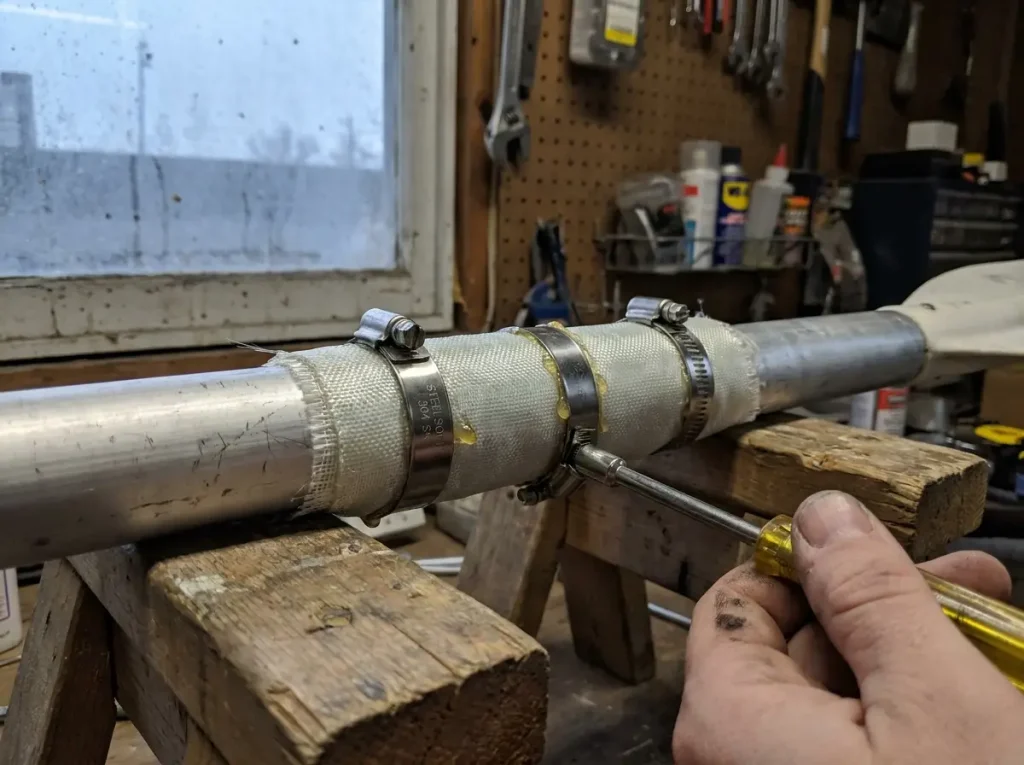 Stainless hose clamps wrapping a fiberglass-wrapped paddle shaft during cure