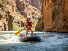 The Rafter’s Guide to the River Rescue Hierarchy A beautiful and athletic female rafter in a red bikini and safety gear, standing on her raft and scouting a challenging rapid in a sunny canyon.