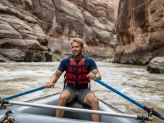 The Science of Cataract Canyon: A Geologic River Guide A male rafter in his early 30s expertly navigates the powerful whitewater rapids of Cataract Canyon, with towering geological formations in the background.