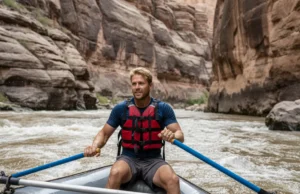 The Science of Cataract Canyon: A Geologic River Guide A male rafter in his early 30s expertly navigates the powerful whitewater rapids of Cataract Canyon, with towering geological formations in the background.
