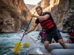 Whitewater Oar Stroke Biomechanics: A Complete Analysis A male rafter in his early 30s executes a perfect oar stroke while navigating a whitewater rapid in a sunny canyon.