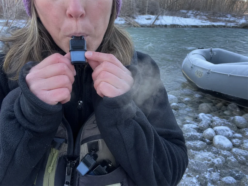 Cold hands test-blowing a Fox 40 Sonik Blast whistle at an icy early-season put-in