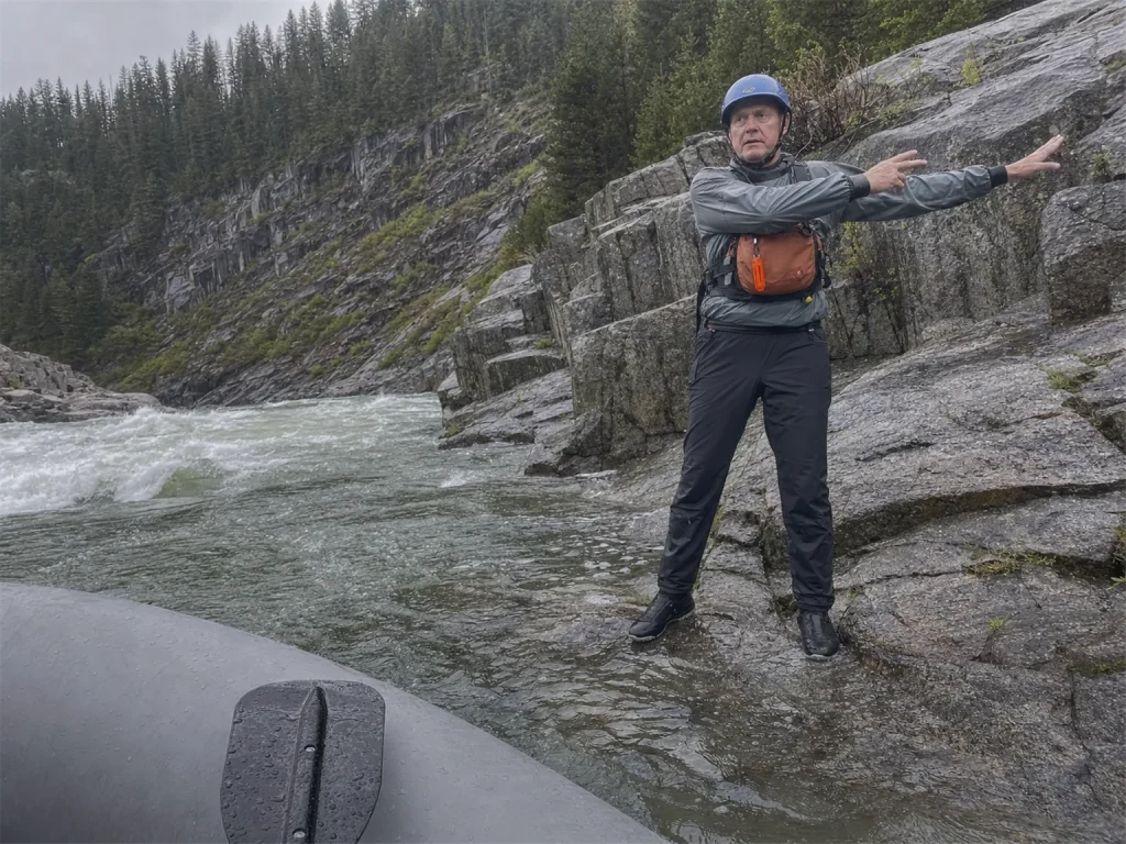 Rafter on shore giving a paddle hand signal while a whistle hangs on the PFD strap