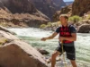 The Definitive 5:1 Rigging Guide for Whitewater Rafters A male rafter in a life vest managing a 5:1 rope rescue system on a rocky riverbank.