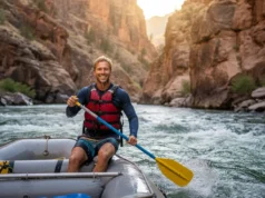 How to Be a Good Rafter: From Gear to Advanced Rapids A confident male raft guide in his early 30s steers a raft through advanced rapids in a sunny canyon.