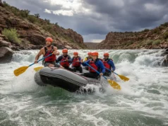 The Rafter’s Field Guide to Keeper Hole Hydraulics A team of rafters in a bright yellow raft paddling hard through a challenging whitewater rapid in a deep canyon.