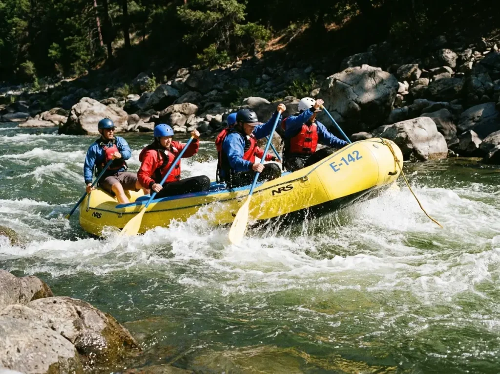 NRS E-142 whitewater raft and paddle crew punching through a wave train