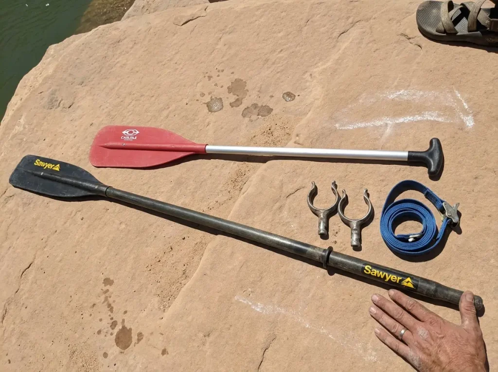 A nine-foot raft oar laid beside a five-foot T-grip paddle showing the hardware difference