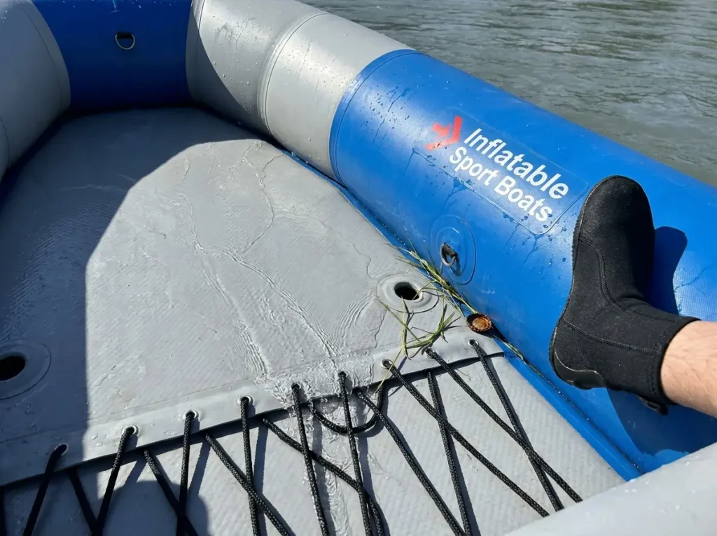 Water draining through the perimeter lacing of a rigid drop-stitch self-bailing raft floor