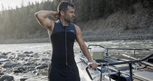 Best Wetsuits for Whitewater Rafting Not Dive Suits Rafter in a 3mm Farmer John wetsuit rigging an oar frame on a cold spring river at dawn