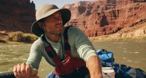 Best Rafting Sun Protection for All-Day River Sun Rafter in a UPF sun hoodie and brimmed hat rowing under bright river-canyon sun