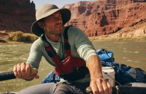 Best Rafting Sun Protection for All-Day River Sun Rafter in a UPF sun hoodie and brimmed hat rowing under bright river-canyon sun