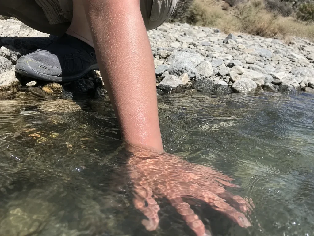 Rafter dipping a hand into cold river water to check temperature before a trip