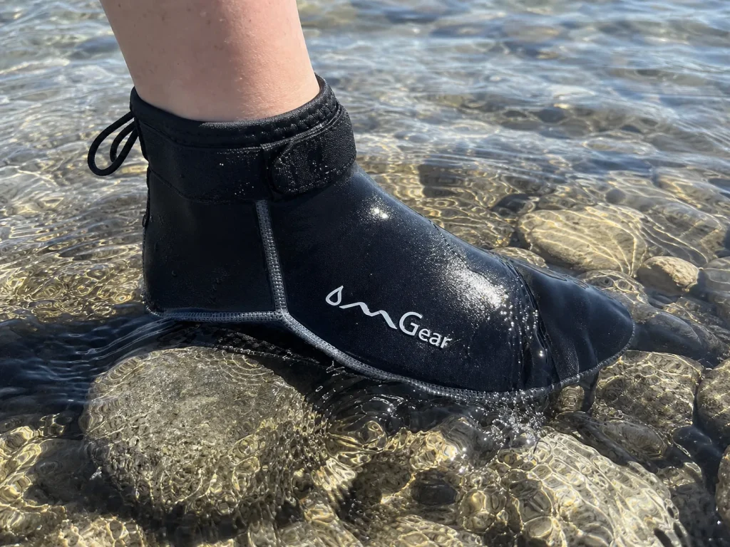 Neoprene sock stepping into cold river shallows showing the trapped-water warmth layer