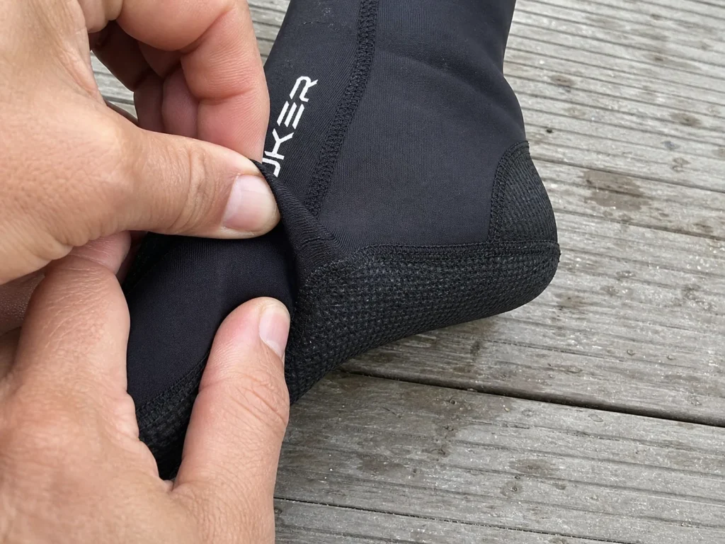Hands stretching a snug neoprene sock over a foot to check the fit against flushing
