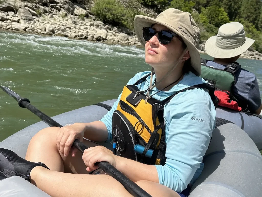Rafter in a UPF sun shirt and wide-brim hat on a warm summer river float
