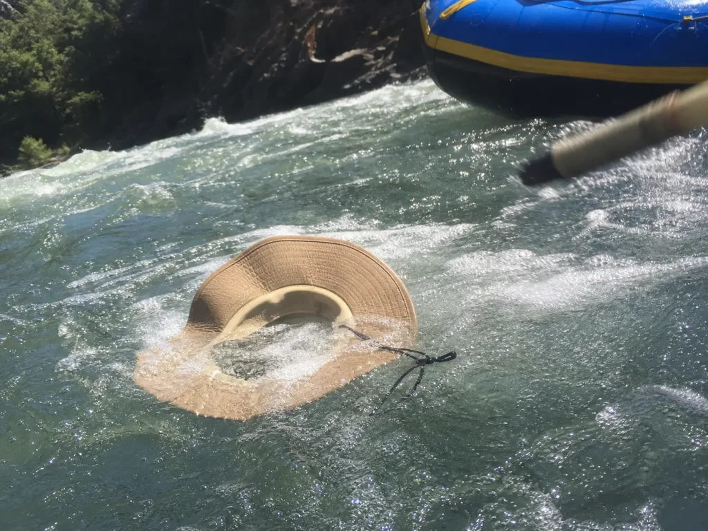 A wide-brim sun hat floating in a river eddy after coming off in a rapid