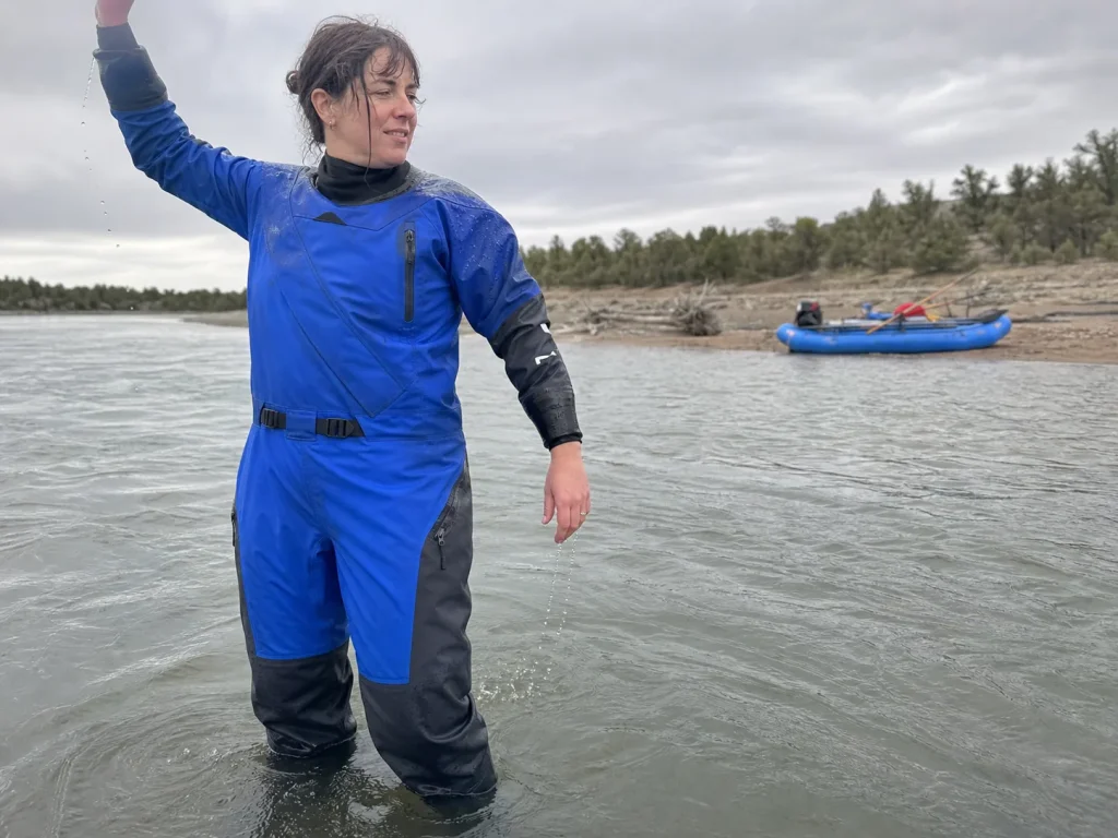 Woman standing in a drysuit in shallow water checking fit and room for insulation layers