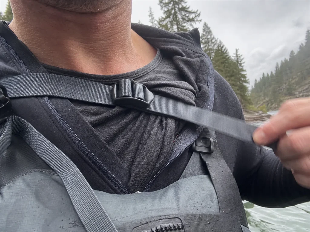 Close view of a base layer bunching under a PFD strap and wetsuit zipper showing rafting fit gotchas