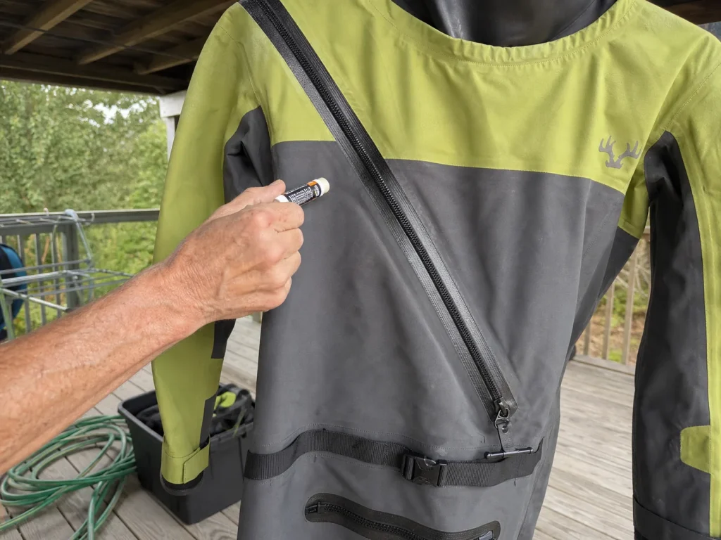Waxing the zipper of a drysuit hung in shade during off-season care and storage