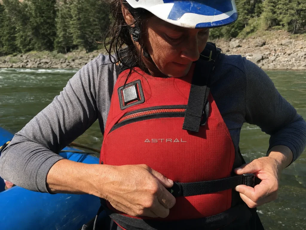 Guide cinching a snug Coast Guard-approved PFD before launch, helmet on