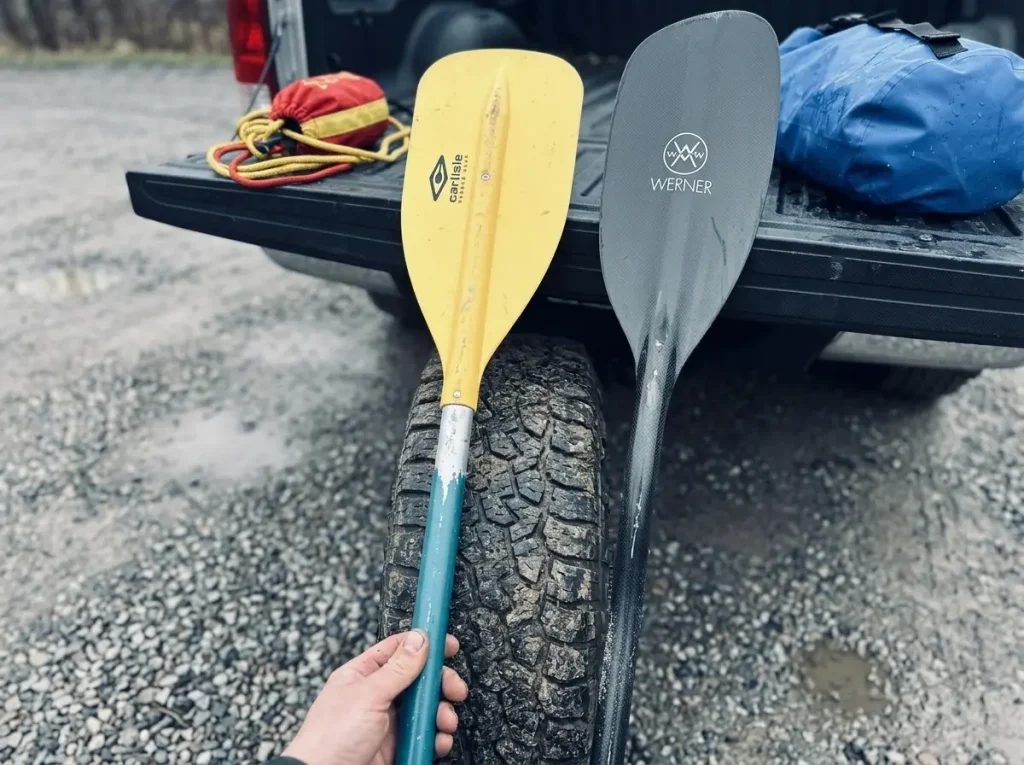 A budget aluminum paddle and a premium carbon paddle leaned together comparing price to value