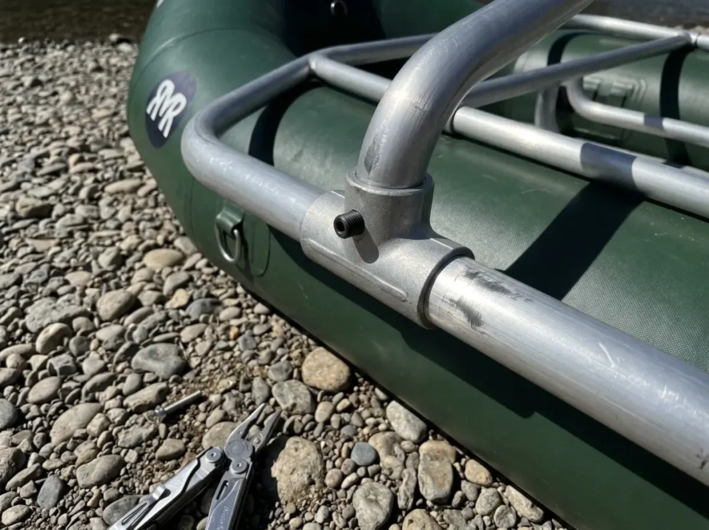 Close-up of a DRE raft frame set-screw Tee fitting and thick aluminum tube on gravel