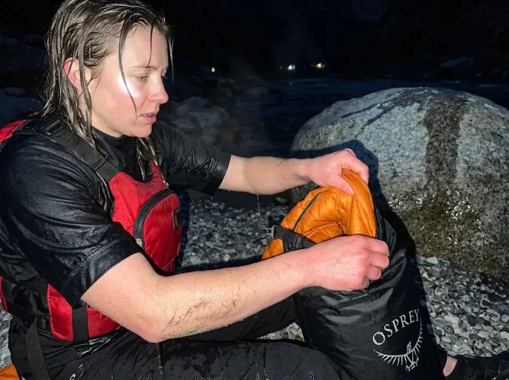 Rafter pulling a dry insulating puffy from an Osprey dry sack after a cold swim