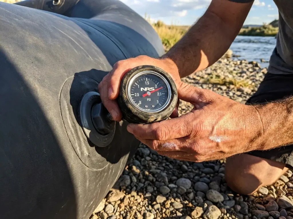 Mechanical raft pressure gauge pressed to an NRS valve reading tube pressure on the bank
