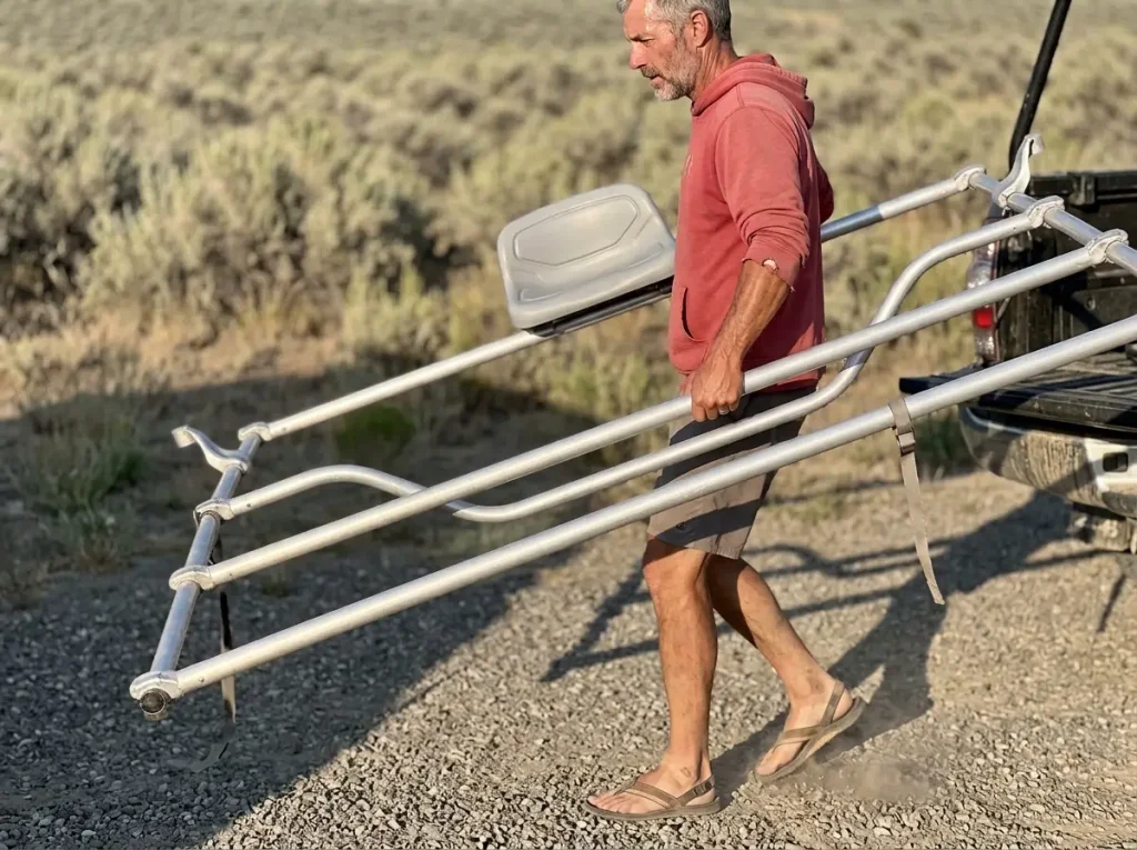 Boater lifting a lightweight NRS Bighorn raft frame off a truck rack showing frame weight